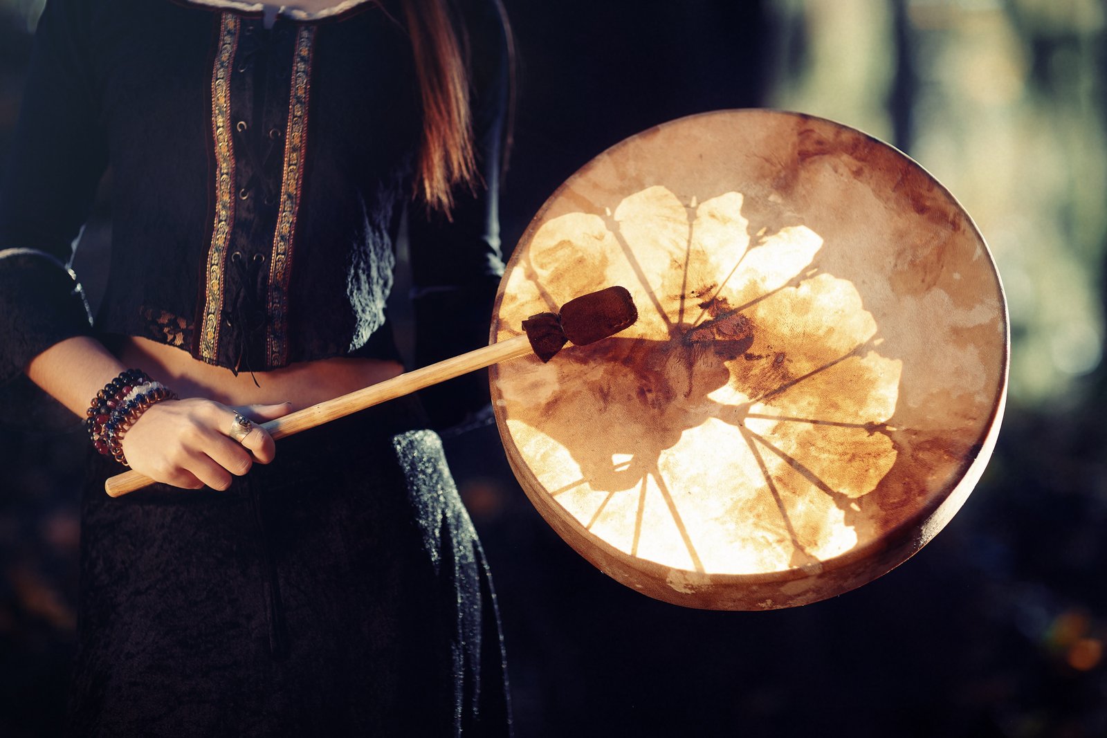 beautiful shamanic girl playing on shaman frame drum in the nature